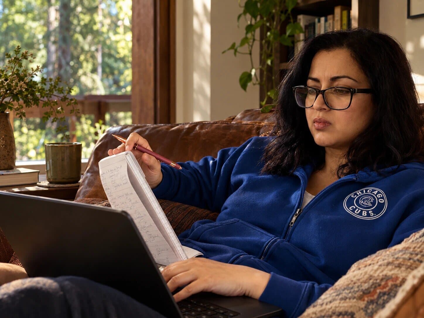 Arushi Sharma Frank reading through a printed draft, pencil in hand, her laptop open on her lap
