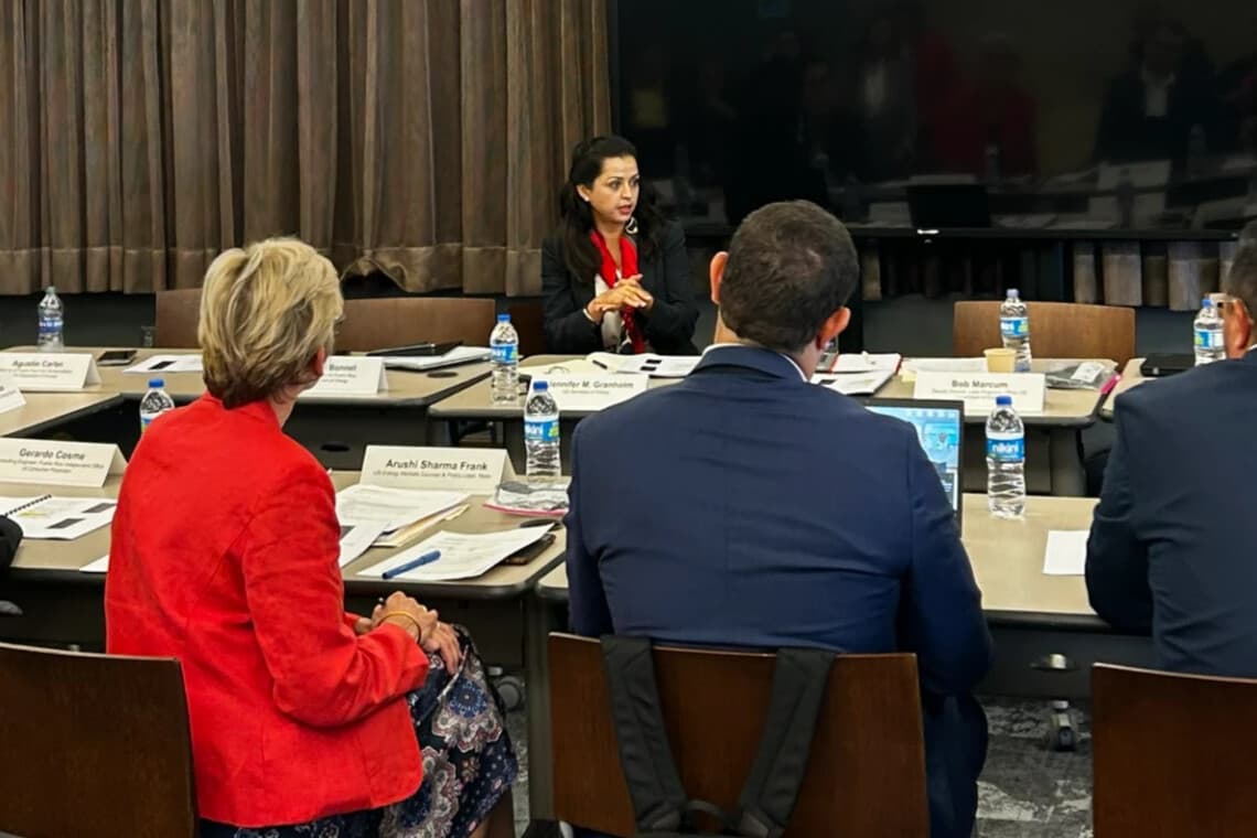Arushi Sharma Frank speaking from the head of a roundtable, behind Secretary Jennifer Granholm’s name card, with officials seated around the tables